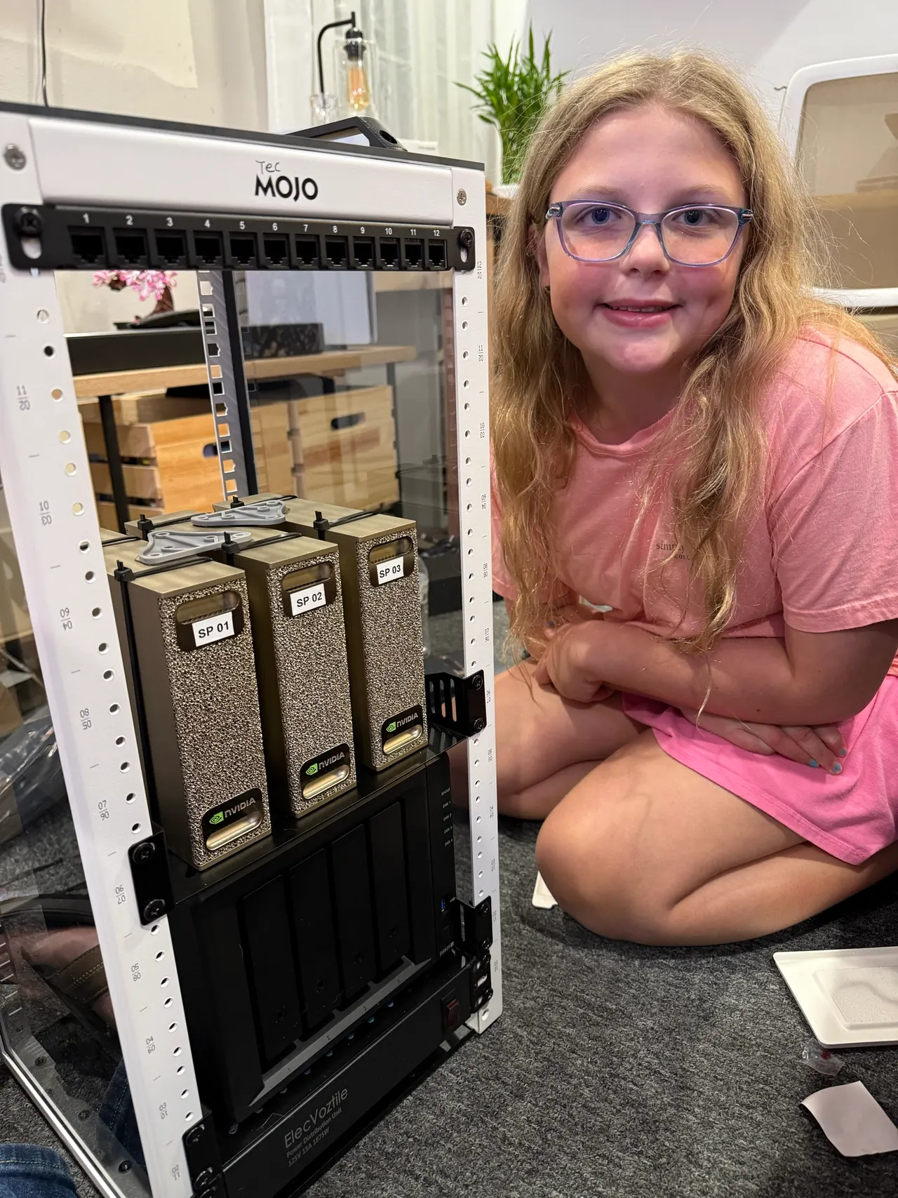 Shannon’s daughter beside the rack with three DGX Sparks installed.